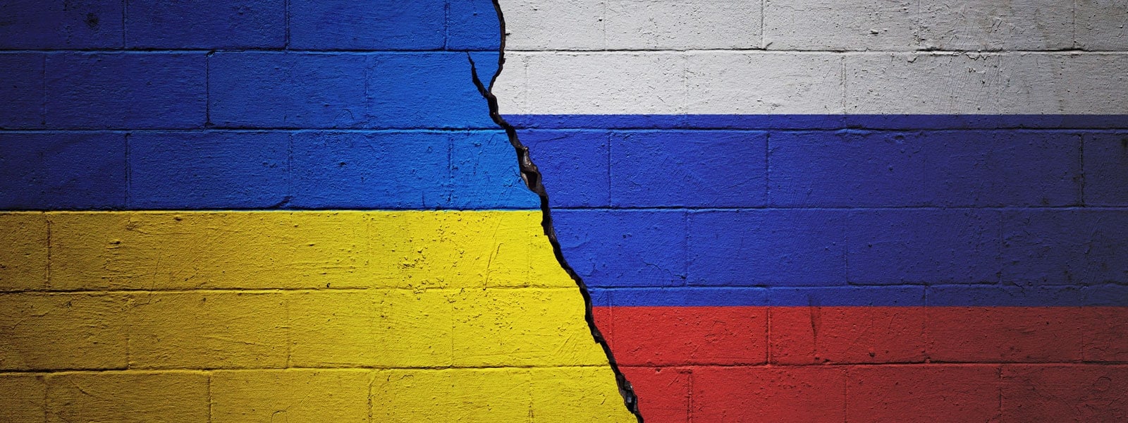 The colors of the Ukrainian and Russian flags on a wall divided by a black crack